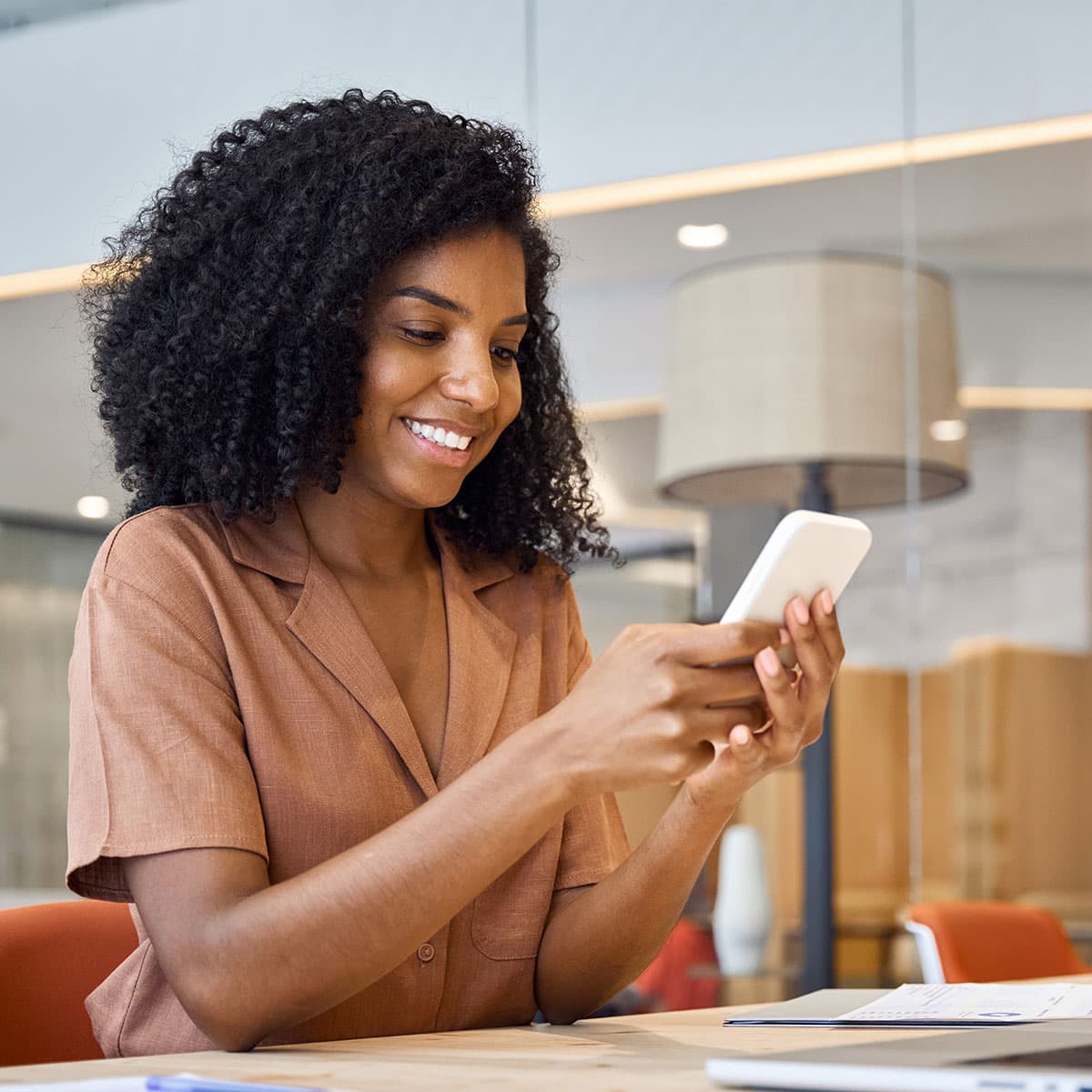 Business owner managing her account on a smartphone with a laptop